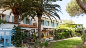 A Mediterranean-style villa with a stone pathway, palm trees, and a well-maintained garden. - Hôtel Sant'Andrea, The Originals Relais (Relais du Silence) (Marciana)
