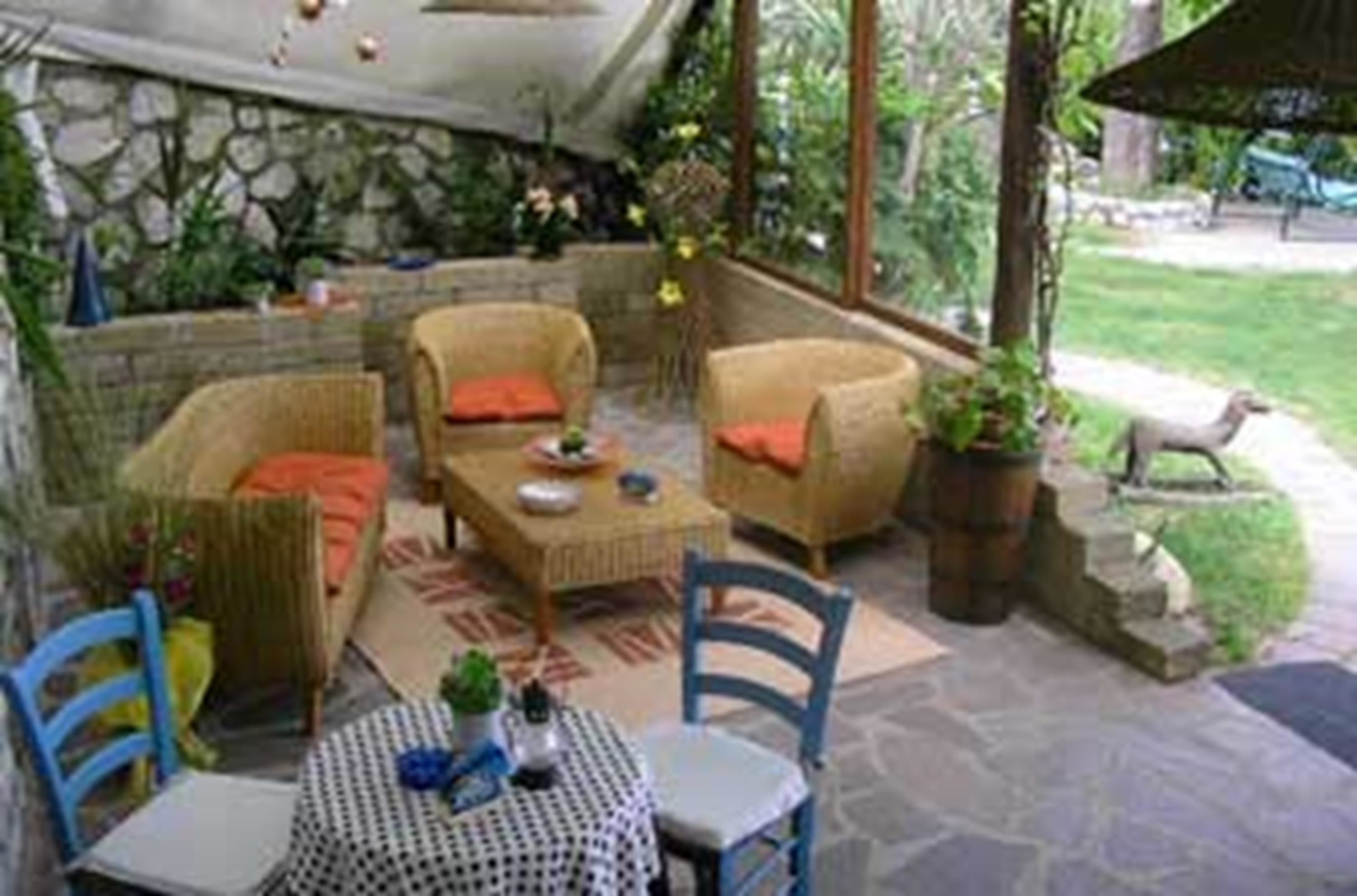 An outdoor patio area with wicker furniture, a round table, and chairs.