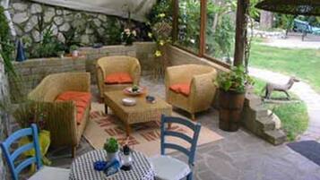 An outdoor patio area with wicker furniture, a round table, and chairs.