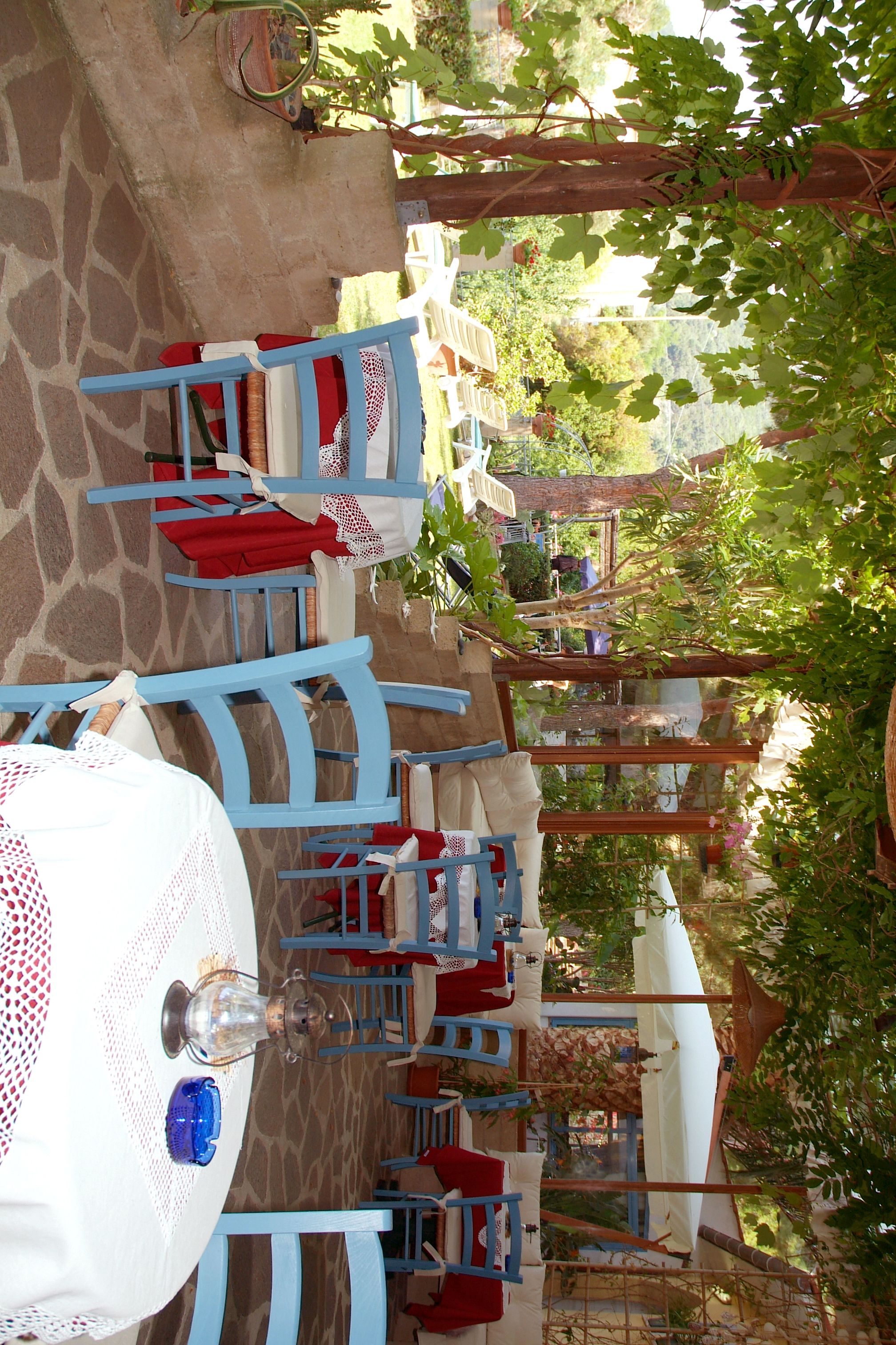 An outdoor dining area with stone flooring, blue chairs, and white tables.