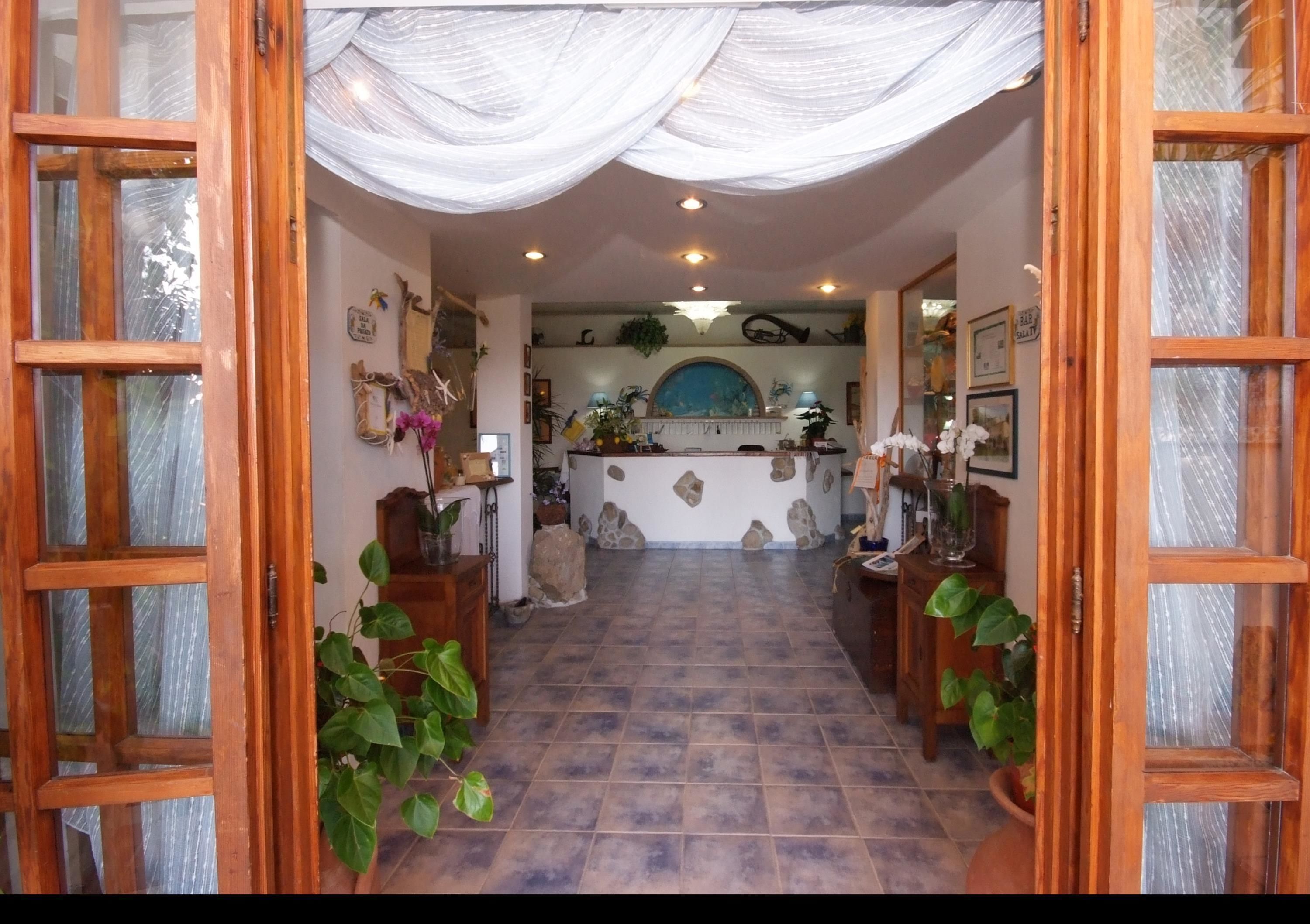 Un área de recepción con mostrador, plantas en macetas y suelo de baldosas.