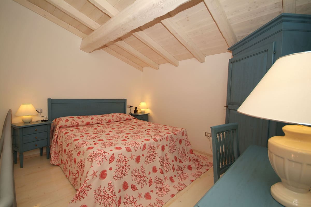 A bedroom with a bed, nightstands, a lamp, and a wardrobe.