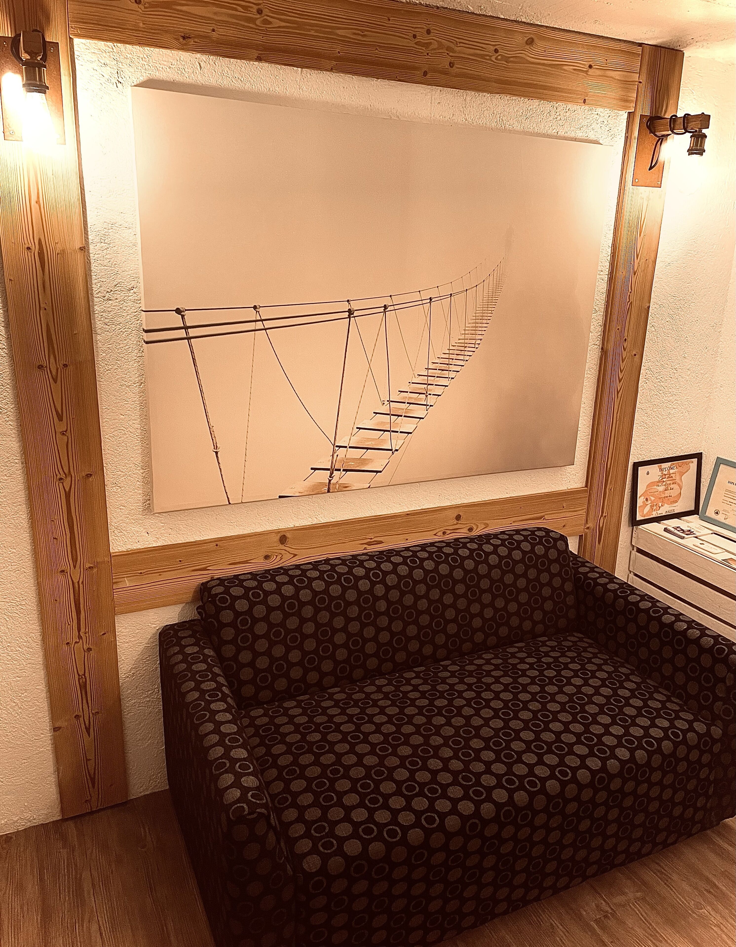 Una habitación con un cabecero de madera, un sofá estampado y un cuadro abstracto de gran tamaño.