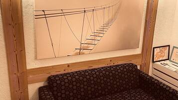 Una habitación con un cabecero de madera, un sofá estampado y un cuadro abstracto de gran tamaño.