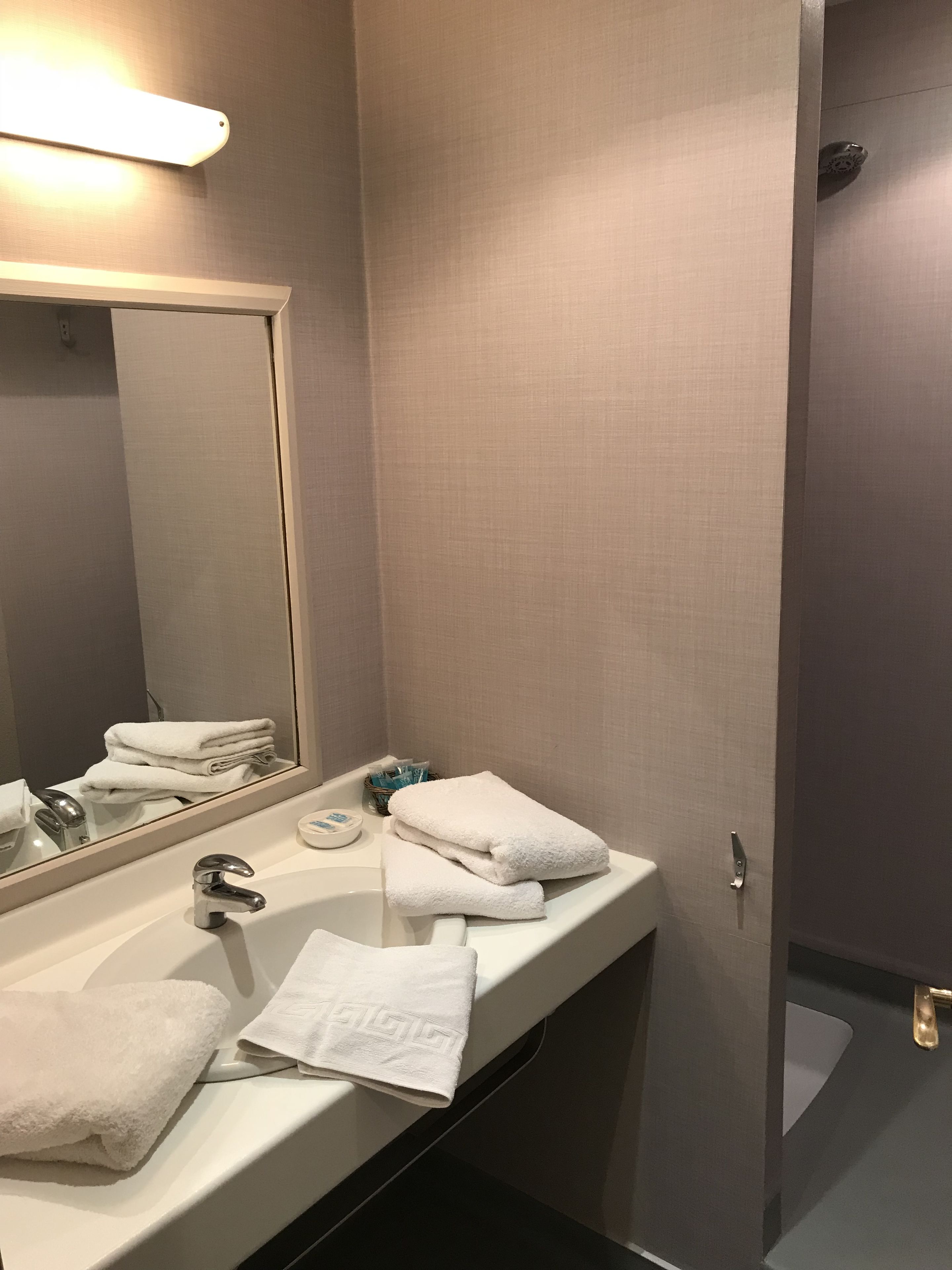 Une salle de bain avec un lavabo blanc, un miroir et un porte-serviettes.