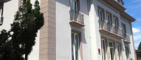 Un edificio grande de varios pisos con fachada simétrica, múltiples ventanas y balcones.