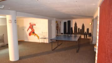 Enjoy a game of ping pong in this vibrant room featuring a city skyline mural and a fun cartoon character.