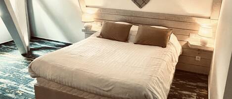 A neatly made bed with a heart-shaped headboard, two bedside lamps, and a wooden nightstand.
