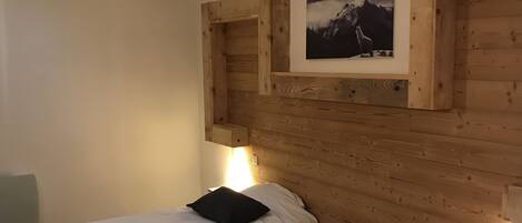 Habitación con dos camas, cabecero de madera, un cuadro enmarco y un tragaluz.