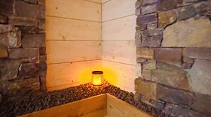 A stone wall corner with a recessed area containing a glowing light fixture.