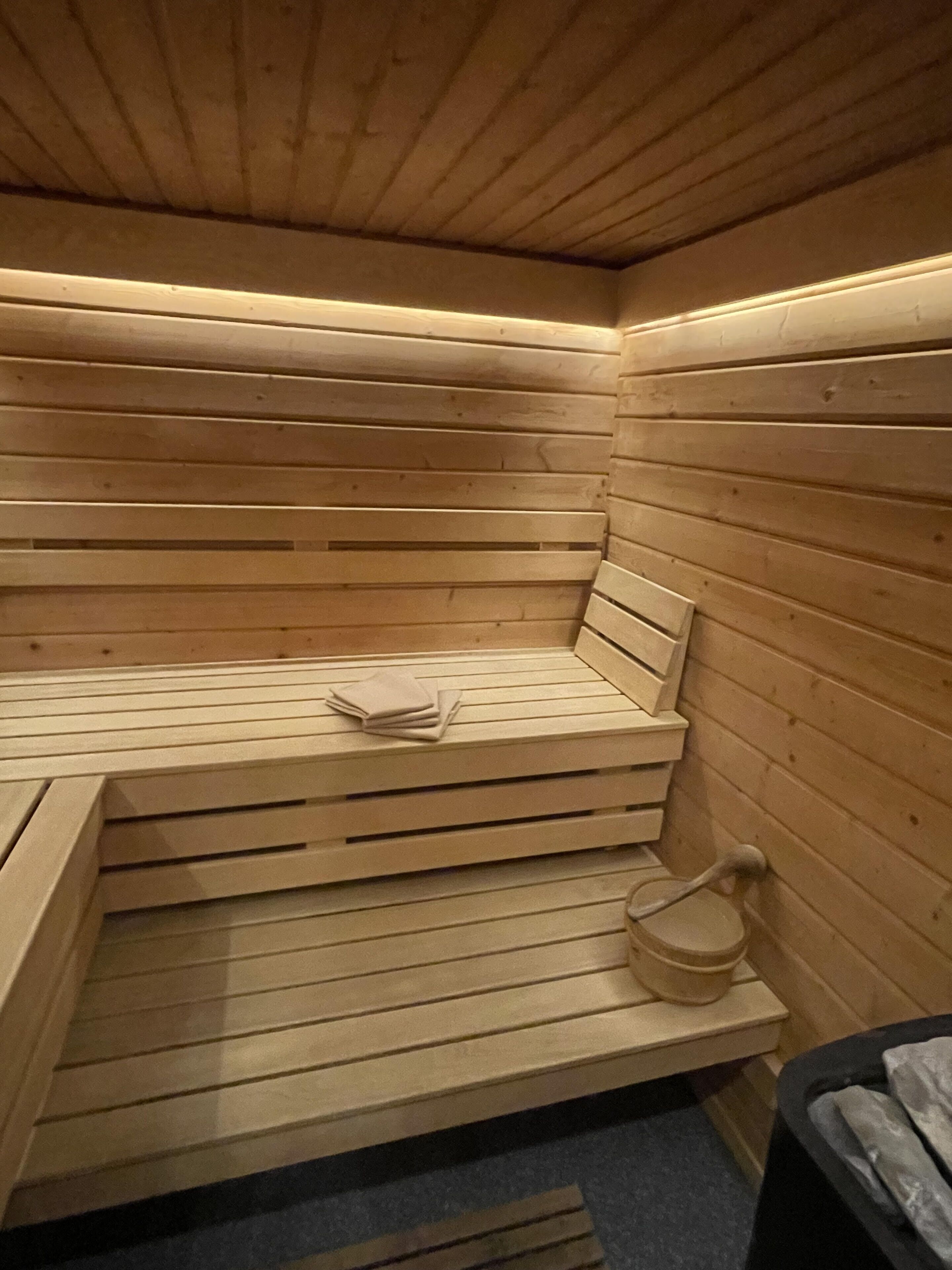 Un sauna en bois avec des bancs et un seau.