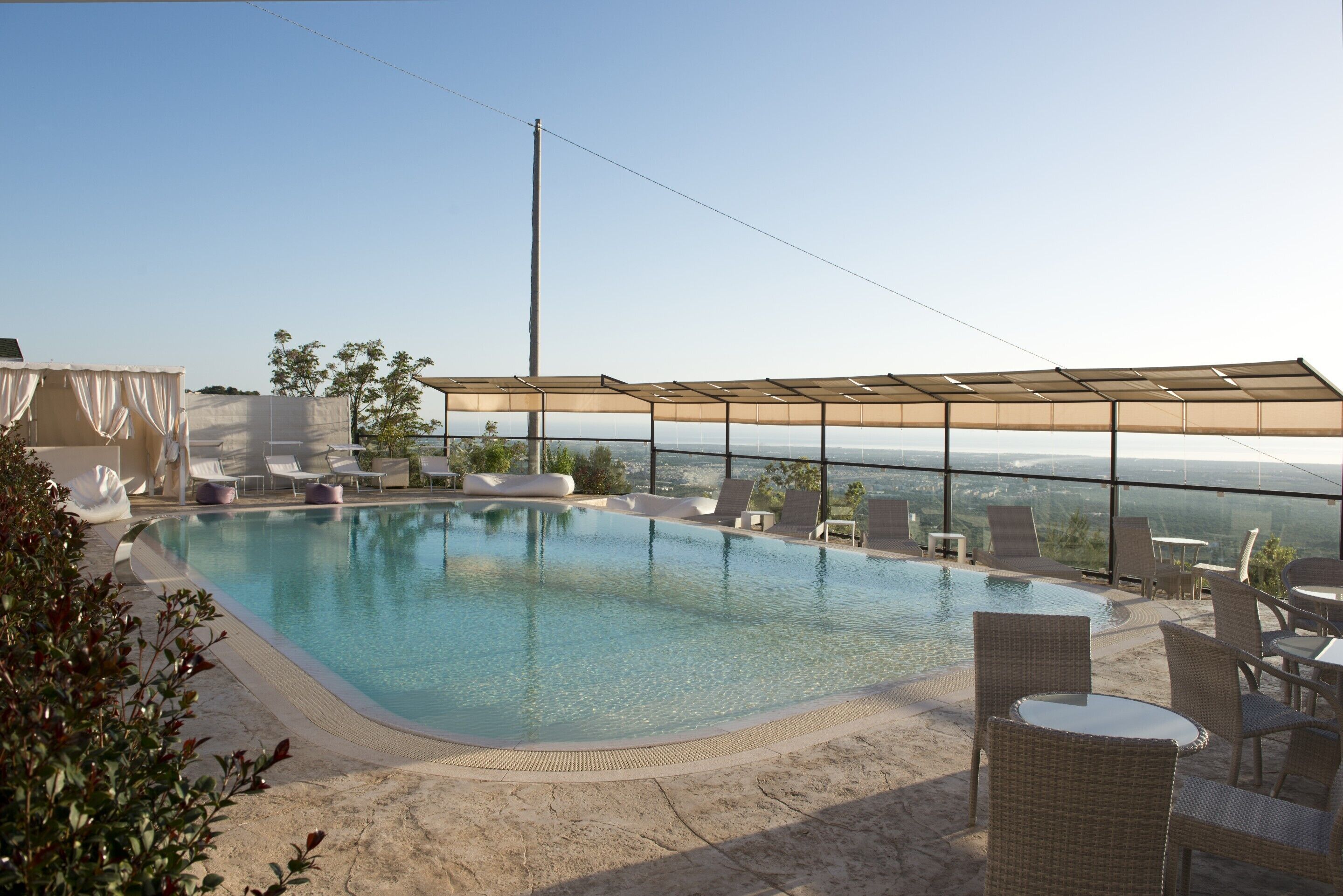 A rooftop pool with clear views of the city skyline, surrounded by lounge chairs and a covered seating area.
