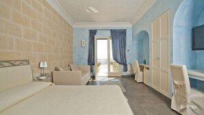 Habitació d'hotel amb un llit gran, un sofà, un escriptori i una cadira. Hi ha un armari i una televisió penjada a la paret.
