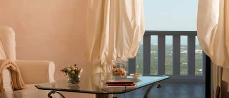 A balcony with a glass table, a chair, a vase with flowers, and a bowl of cookies.