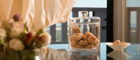Un bocal en verre rempli de biscuits est posé sur une table, avec un vase de fleurs en premier plan.