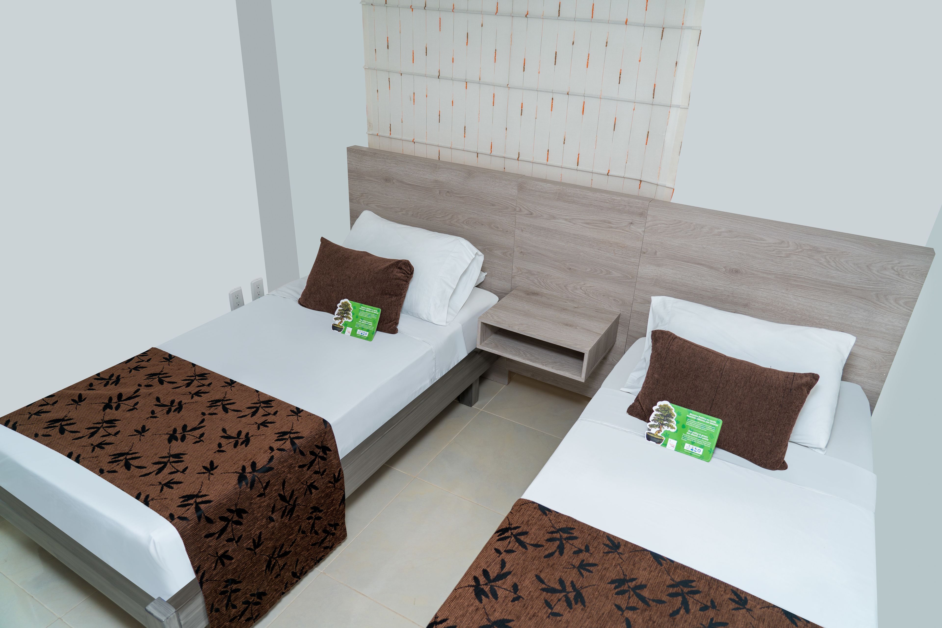 Two single beds with wooden headboards, white bedding, and brown throw pillows.