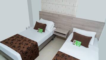 Two single beds with wooden headboards, white bedding, and brown throw pillows.