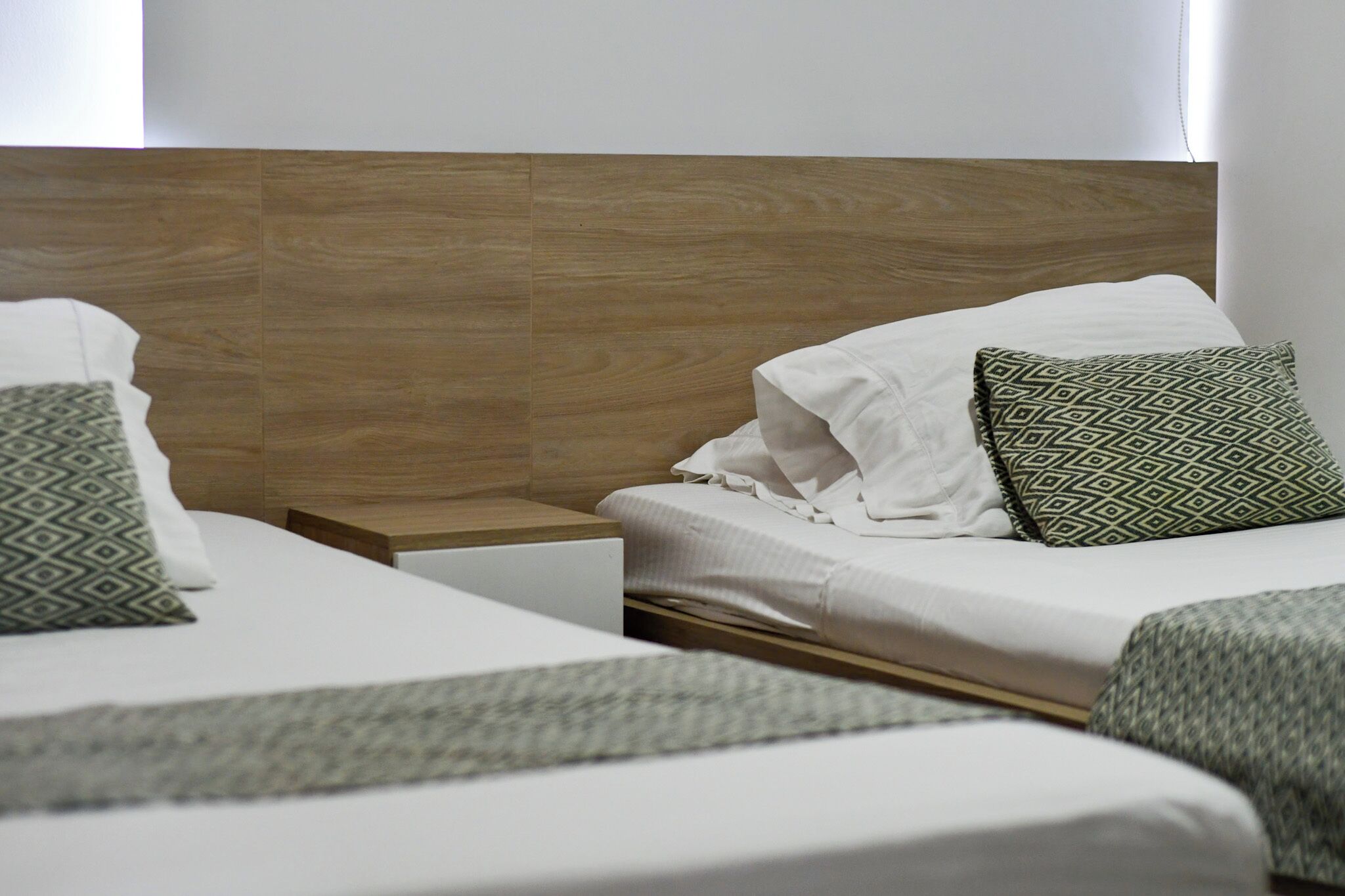 A hotel room with two beds, a wooden headboard, and a nightstand.