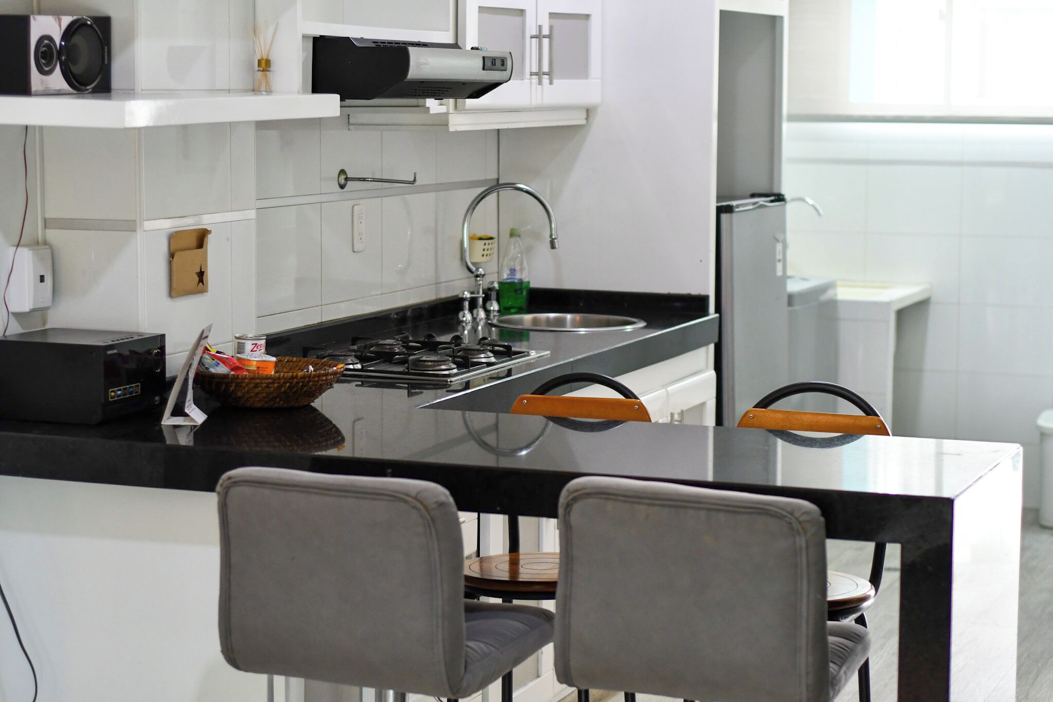 A modern kitchen with white cabinets, a black countertop, and a stainless steel sink.