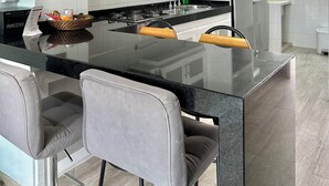 Una cocina moderna con una isla central, taburetes de bar y un horno empotrado.