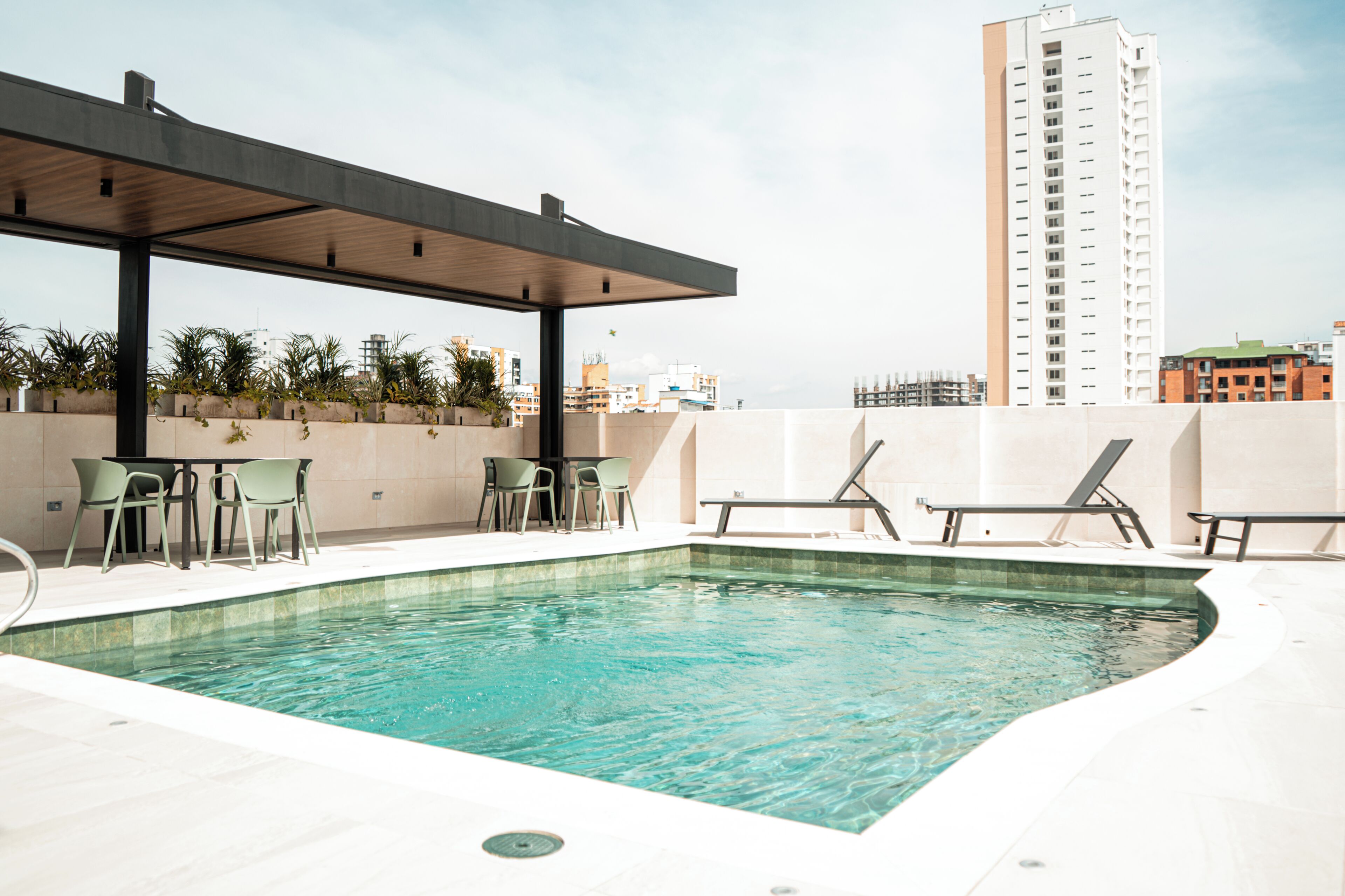 An outdoor swimming pool with lounge chairs and a covered seating area.