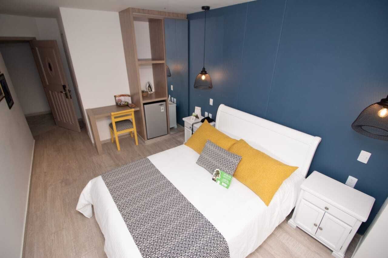 Un dormitorio con cama, mesita de noche y escritorio con silla.