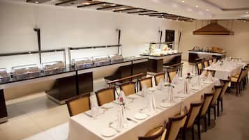 A buffet setup with multiple serving stations and a long dining table set for a meal.