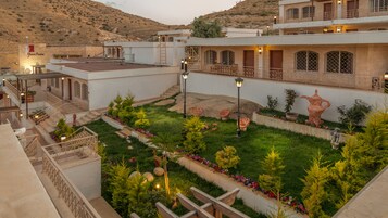 Un hotel con un patio que cuenta con un jardín, mobiliario exterior y una escalera que lleva a los pisos superiores.