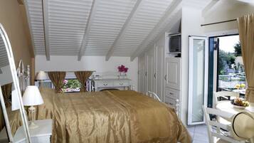 A bedroom with a bed, bedside tables, a dresser, a TV, and a balcony with a table and chairs.