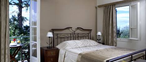 A bedroom with a bed, bedside lamps, a nightstand, a dresser, and a window with curtains.