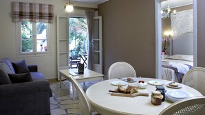 A cozy room with a dining table set for breakfast, a sofa, and a bed with a nightstand. - Dafnoudi (Kefalonia)