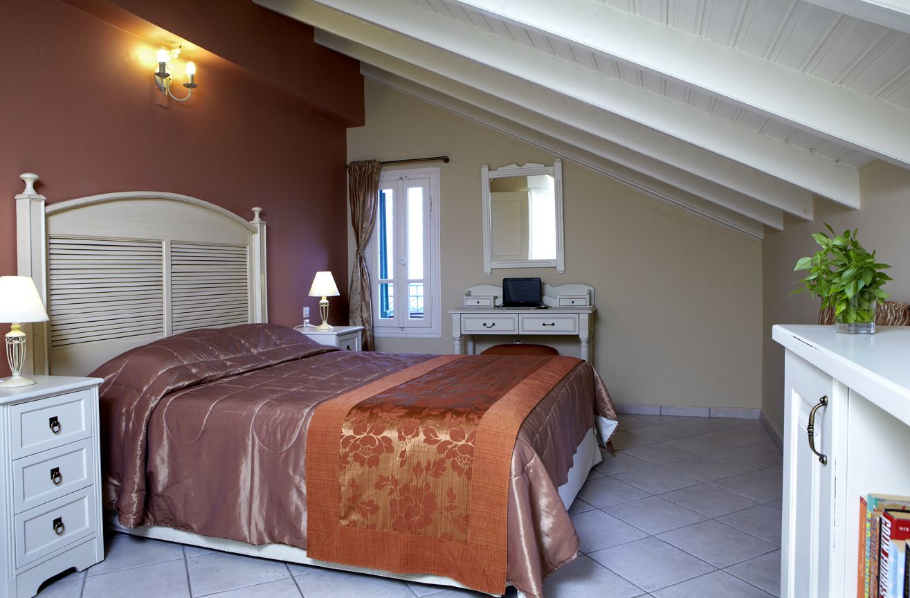 Een slaapkamer met een bed, nachtkastje, lamp, kaptafel en een spiegel.