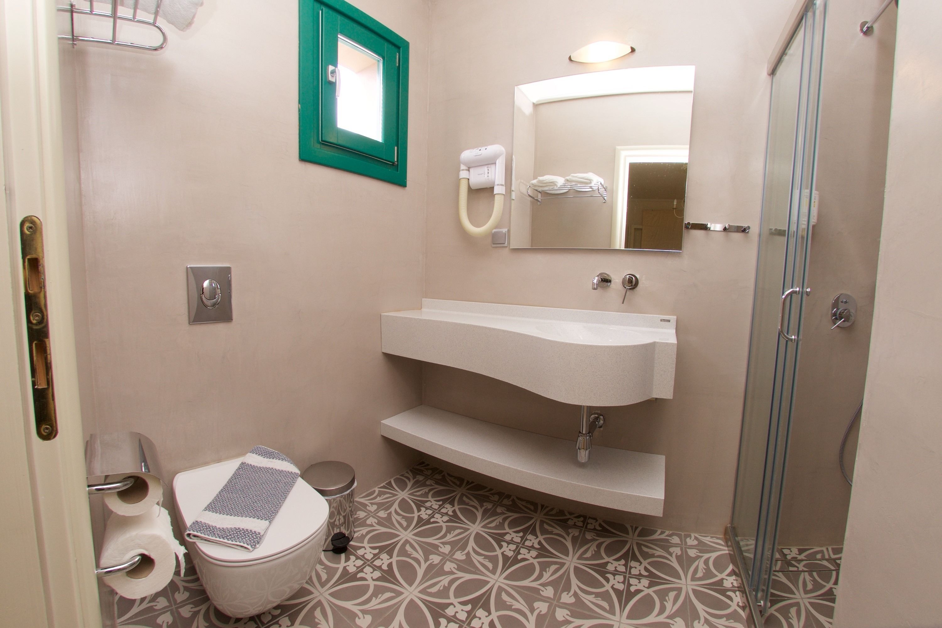 A bathroom with a toilet, sink, mirror, and shower.