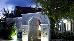 A stone archway leading to a building with a sign that reads "DALLOLI APARTMENTS HN". - Dafnoudi (Kefalonia)
