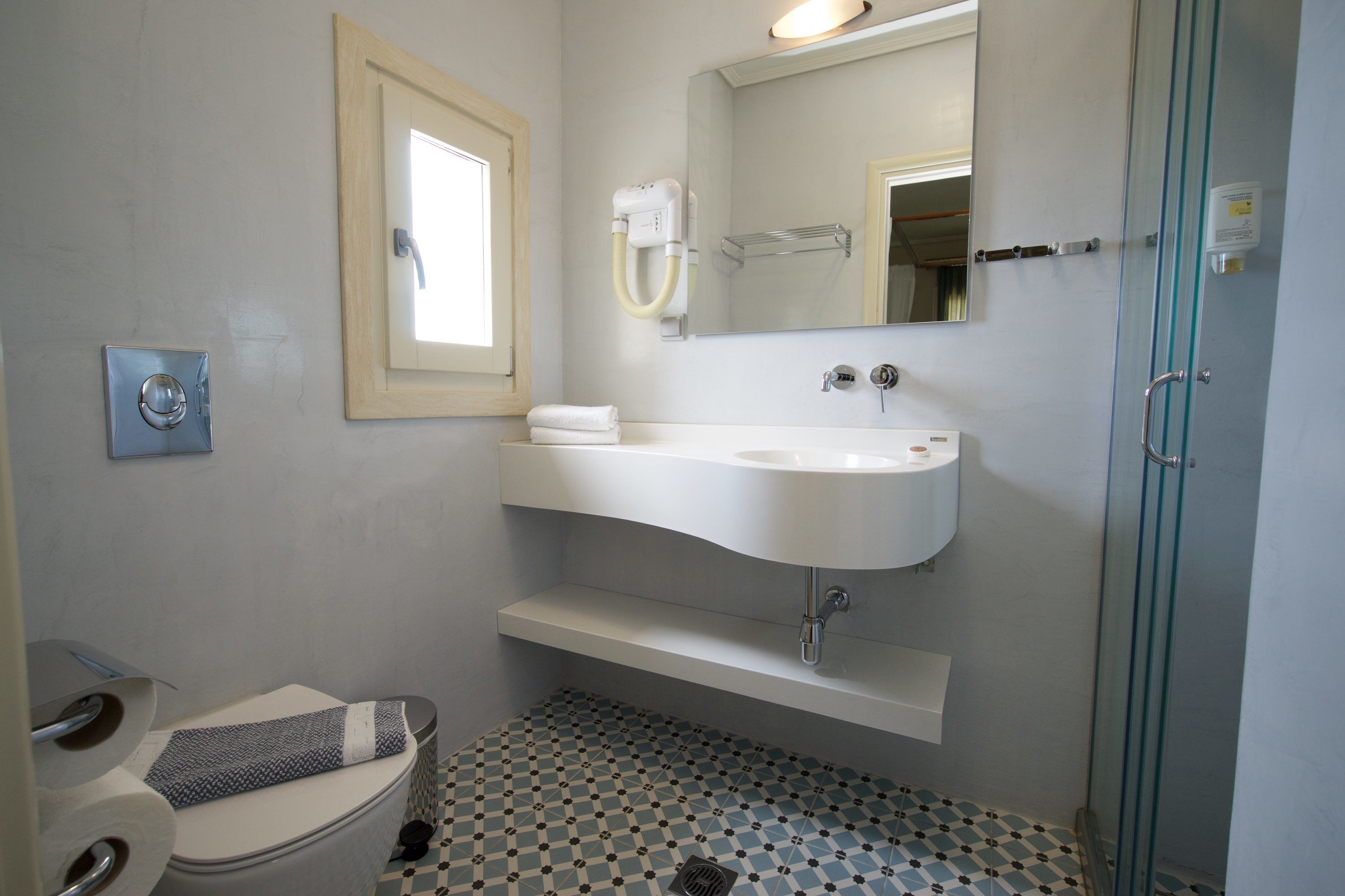 Un baño con inodoro, lavamanos, espejo y ducha.