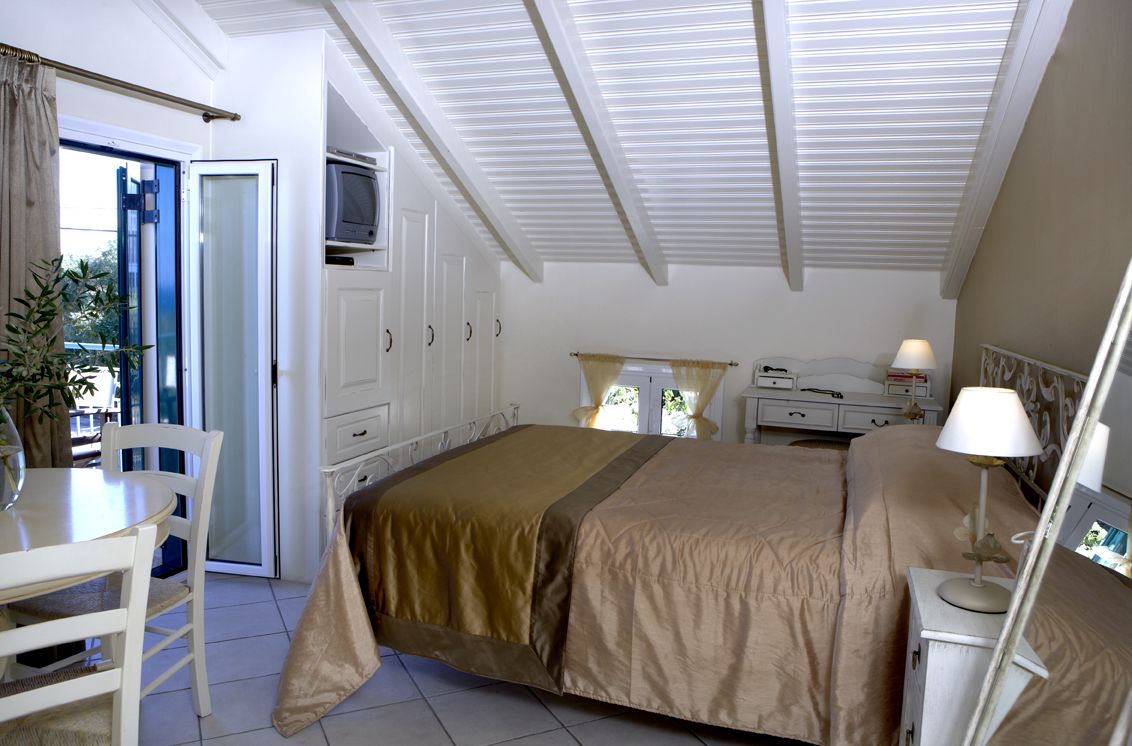 Un dormitorio con cama, escritorio, silla, televisor y ventana.