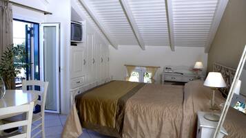 Un dormitorio con cama, escritorio, silla, televisor y ventana.