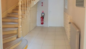 Eine Treppe mit weißen Wangen, die zu einer Zwischenebene führt. Ein Feuerlöscher ist in Wandnähe an der Zwischenebene angebracht.