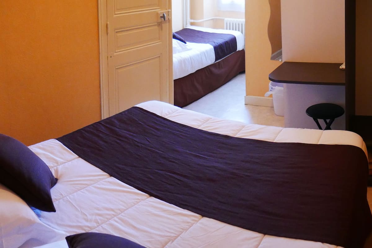 Habitación de hotel con dos camas, un escritorio y una silla.