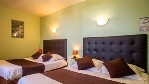 Ein Hotelzimmer mit zwei Betten, jeweils mit Kopfteil, Nachttisch und Lampe sowie einer Wandleuchte.