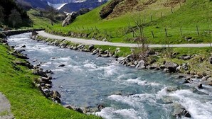 Ein Fluss fließt durch ein Tal, im Hintergrund sind Berge zu sehen.