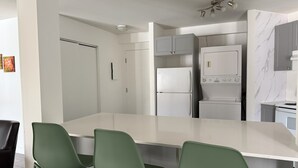 A modern kitchen with a white countertop, green chairs, and built-in appliances. - Condos Vacances MSA CONDO (Beaupre)