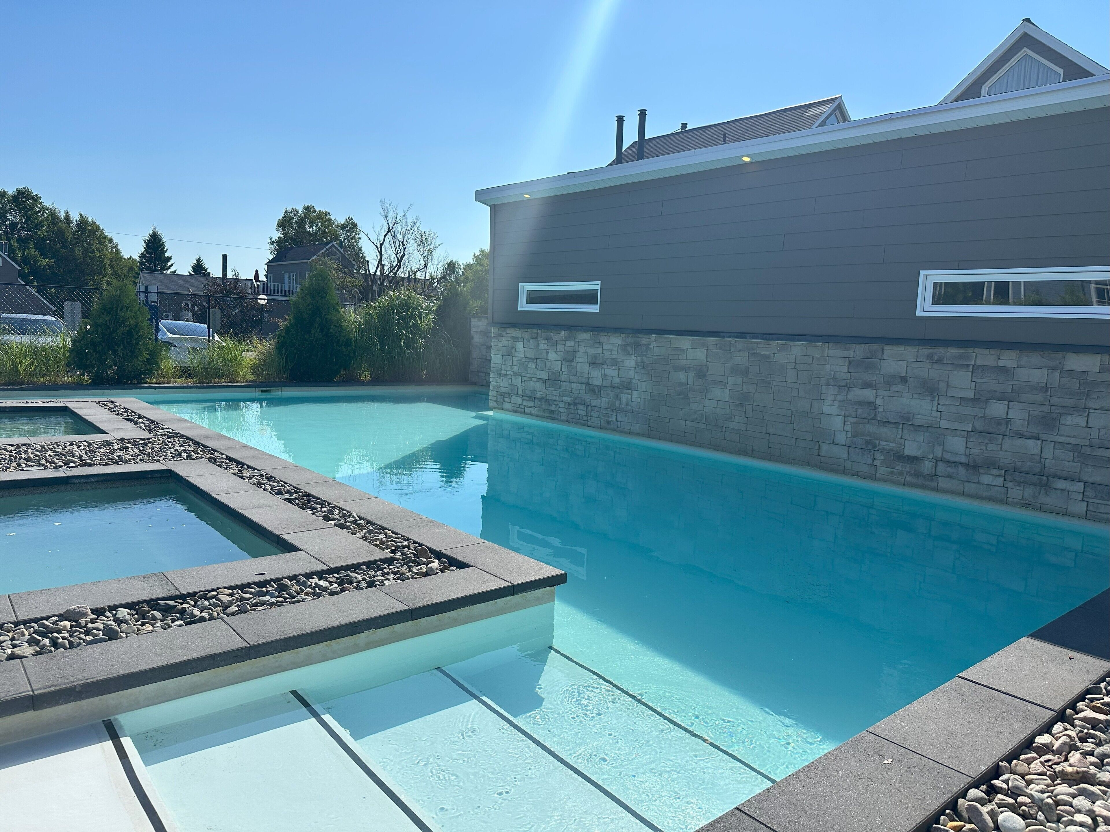 Ein Schwimmbecken mit Steingrenze und einer Steinmauer neben einem modernen Gebäude.