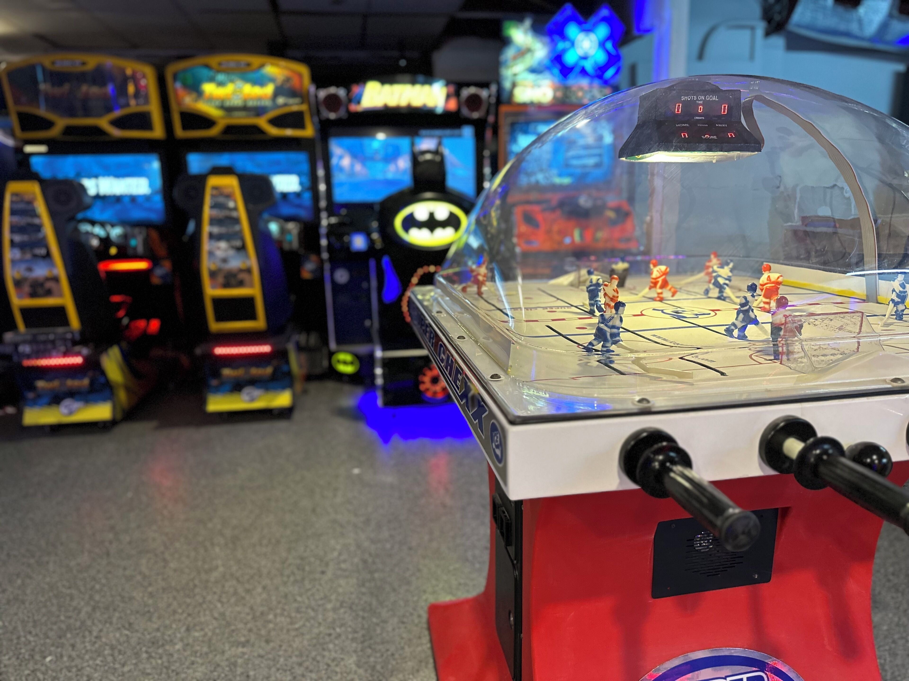 A foosball table with a Batman theme, surrounded by arcade machines.