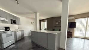 A modern kitchen with grey cabinets, a central island, and a large window. - Condos Vacances MSA CONDO (Beaupre)