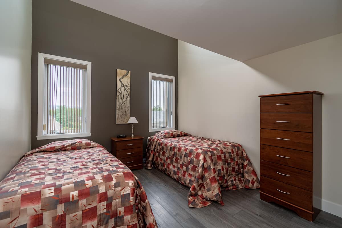 Une chambre avec deux lits, une commode et une table de chevet.