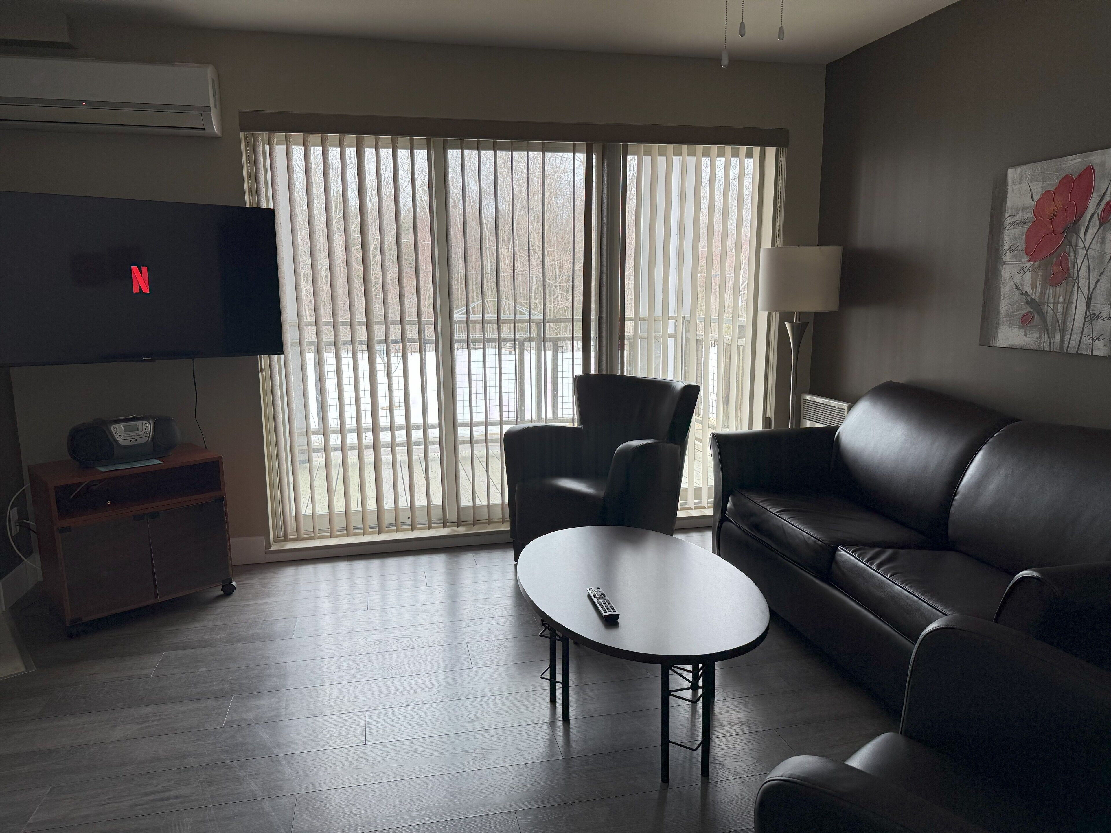 A living room with a TV, a sofa, a table, and a chair.