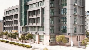 Un edificio moderno con varios pisos, ventanas amplias y techo plano.