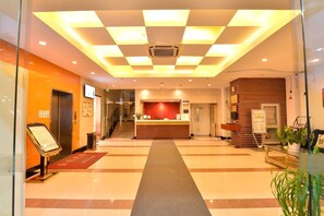 A hotel lobby with a reception desk, a staircase, and a checkered ceiling. - Joyful Star Hotel Pudong Airpot Wanxia (Shanghai)