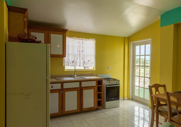 Una cocina con refrigerador, estufa y lavamanos.